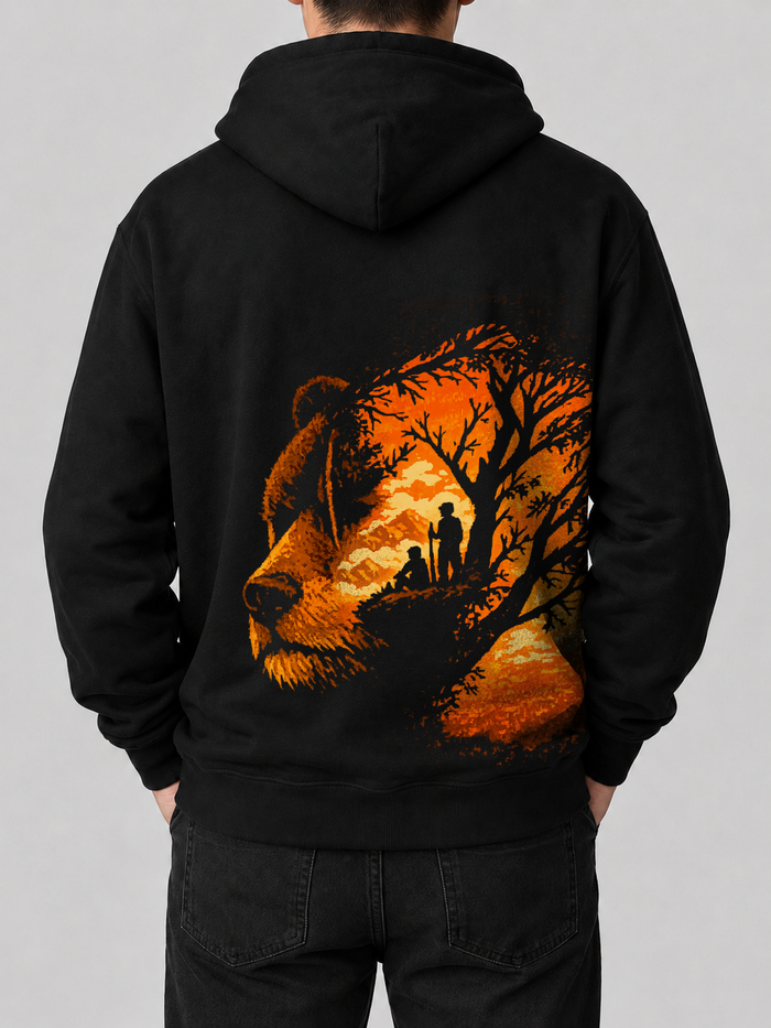 Back of Ruxel Stay Wild hoodie in Void Black - grizzly bear profile double-exposed with a golden sunset forest and two hikers