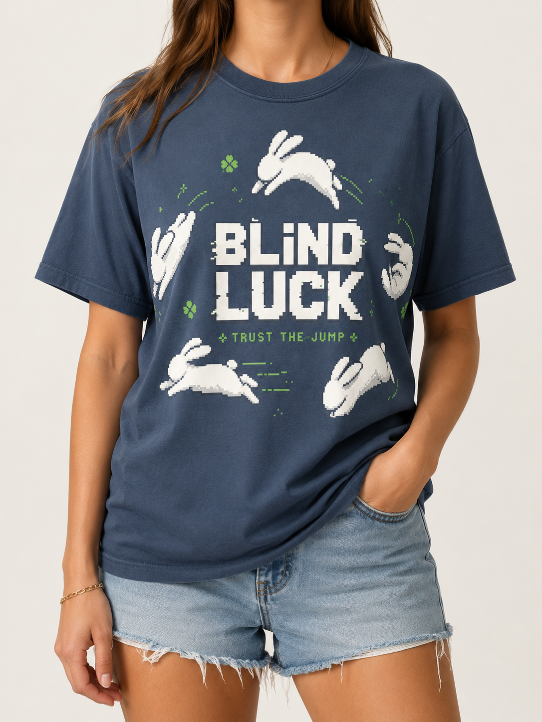 Woman wearing the Ruxel Blind Luck tee in Midnight Navy, front view - pixel-art white rabbits leaping around BLIND LUCK with green four-leaf clovers and Trust the Jump