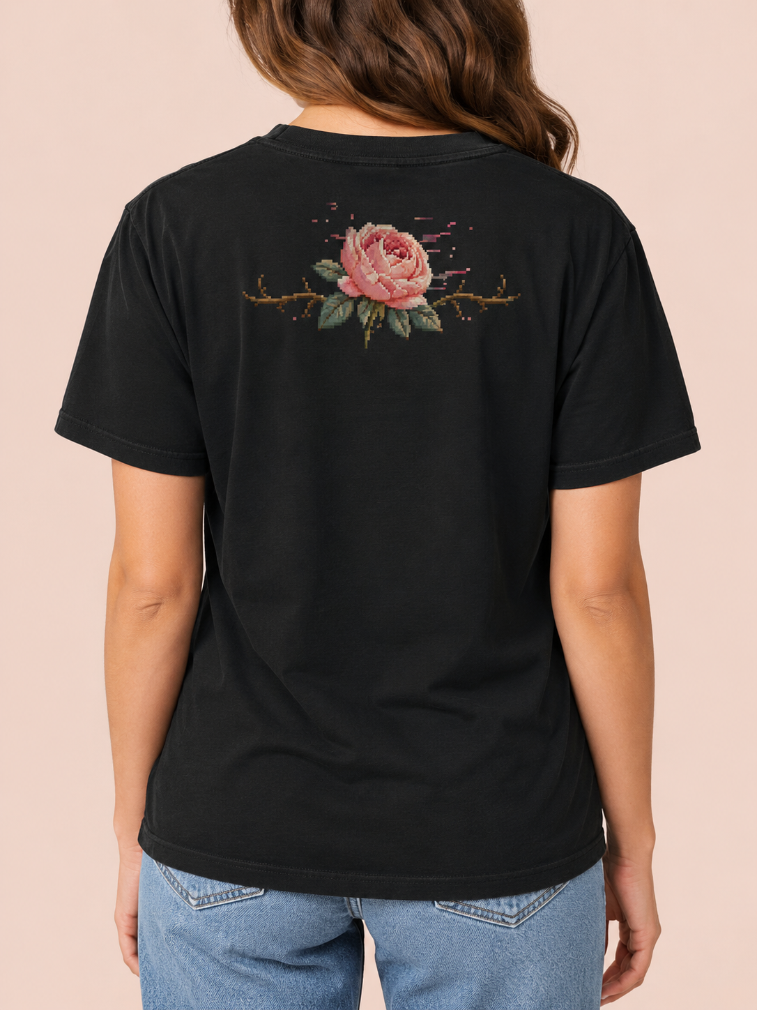 Back of the Ruxel Rosebound Void Black tee worn by a woman - pixel-art pink rose with a thorn vine