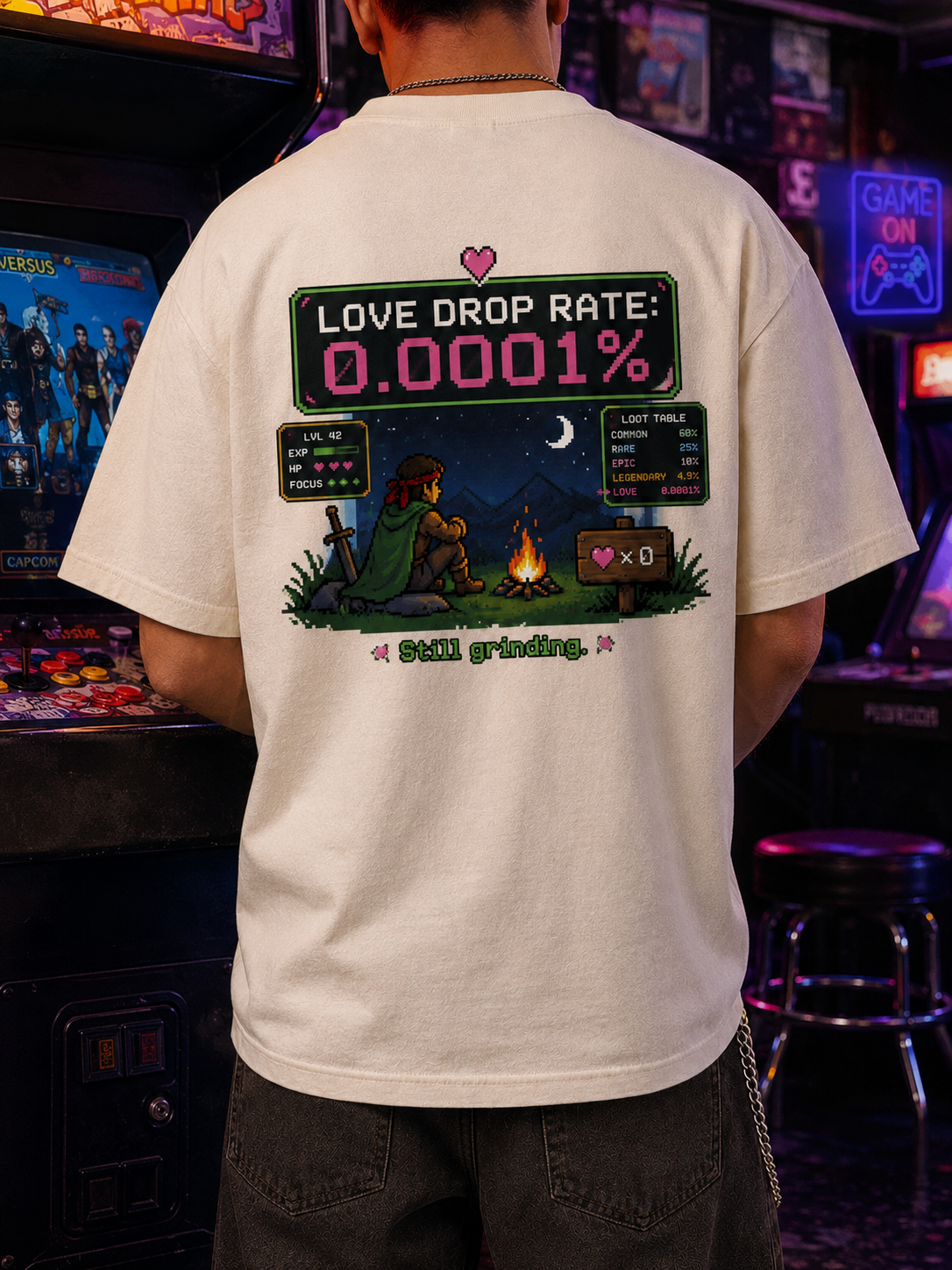 Man on a city rooftop at dusk wearing the Ruxel Love Drop Rate Cream pixel RPG tee, back view showing the loot-screen print