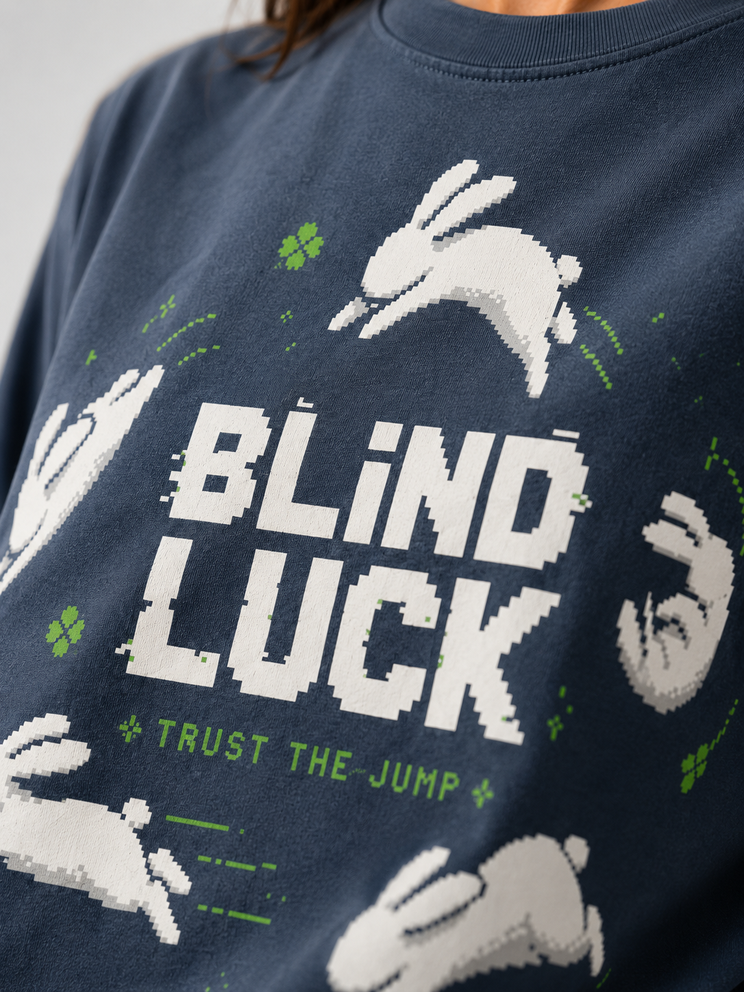 Close-up of the Blind Luck pixel print on Ruxel Midnight Navy garment-dyed cotton - leaping white rabbits, green four-leaf clovers and Trust the Jump