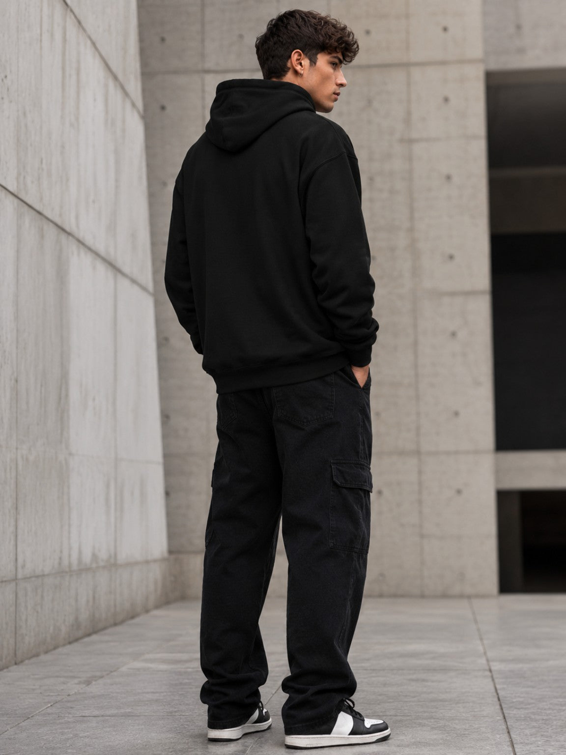 Back three-quarter view of a male model wearing the Ruxel Good Luck Loading Void Black heavyweight hoodie