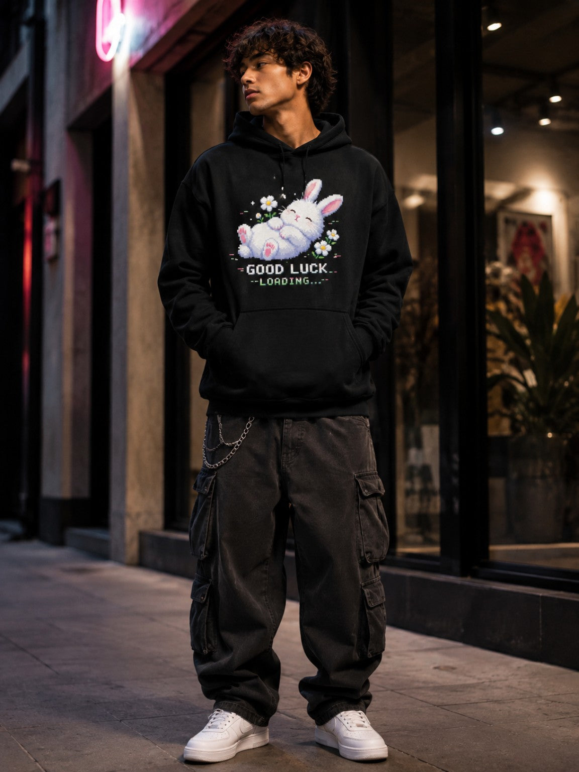 Male model wearing the Ruxel Good Luck Loading Void Black pixel bunny hoodie in an evening streetwear setting