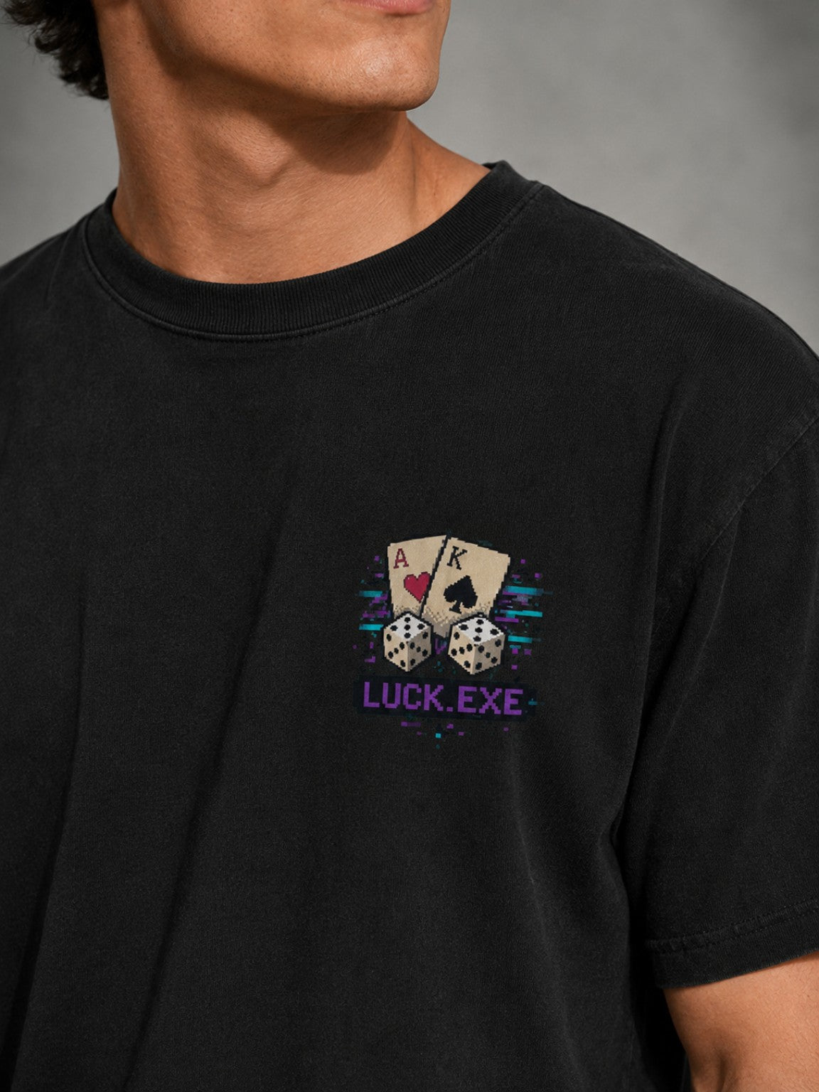Close-up of the Ruxel Luck.exe chest print on Vintage Black cotton, showing pixel-art cards, dice and purple LUCK.EXE lettering