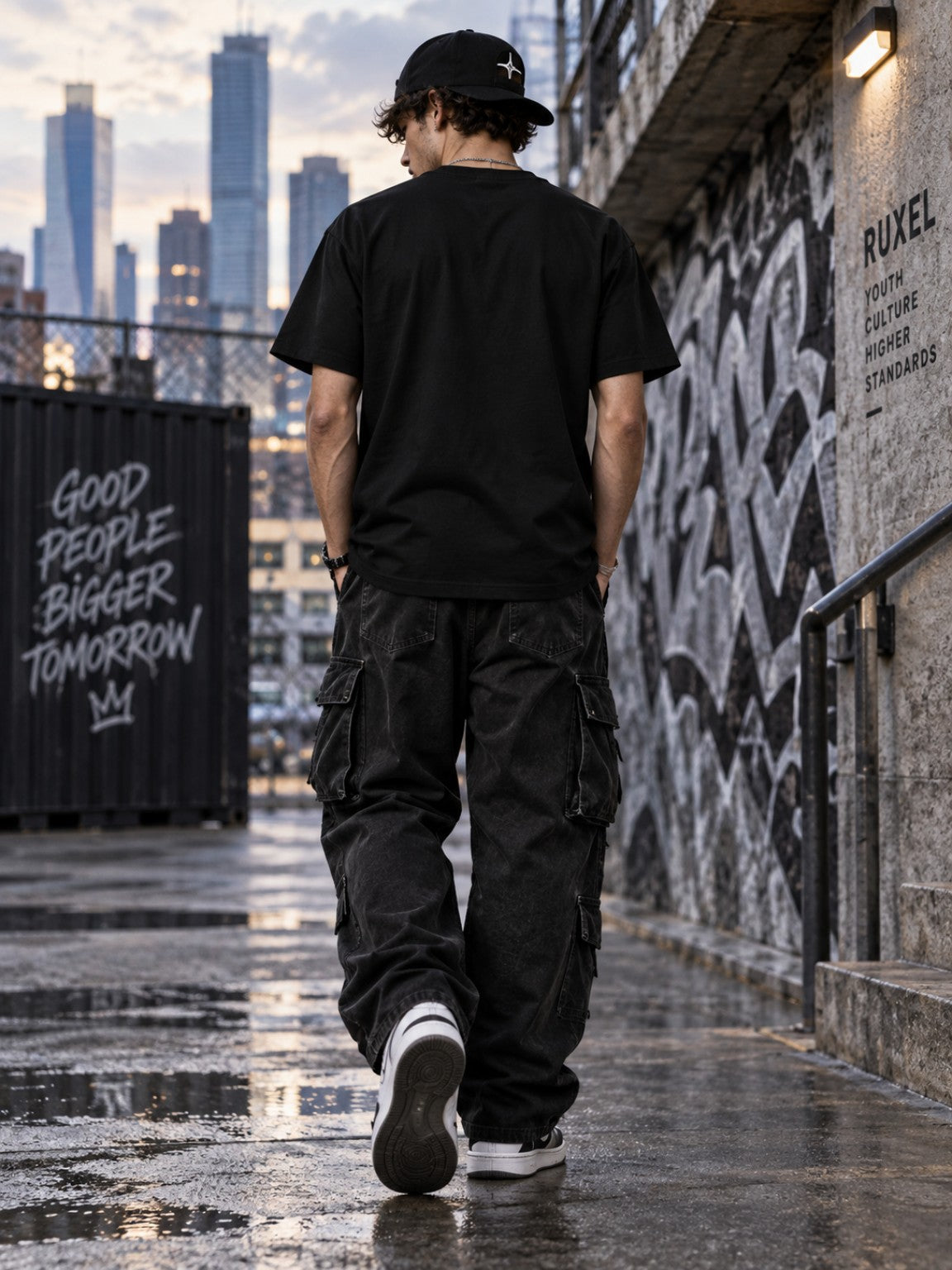 Male model wearing the Tethered Souls Eclipse Black heavyweight tee from the back in a city alley