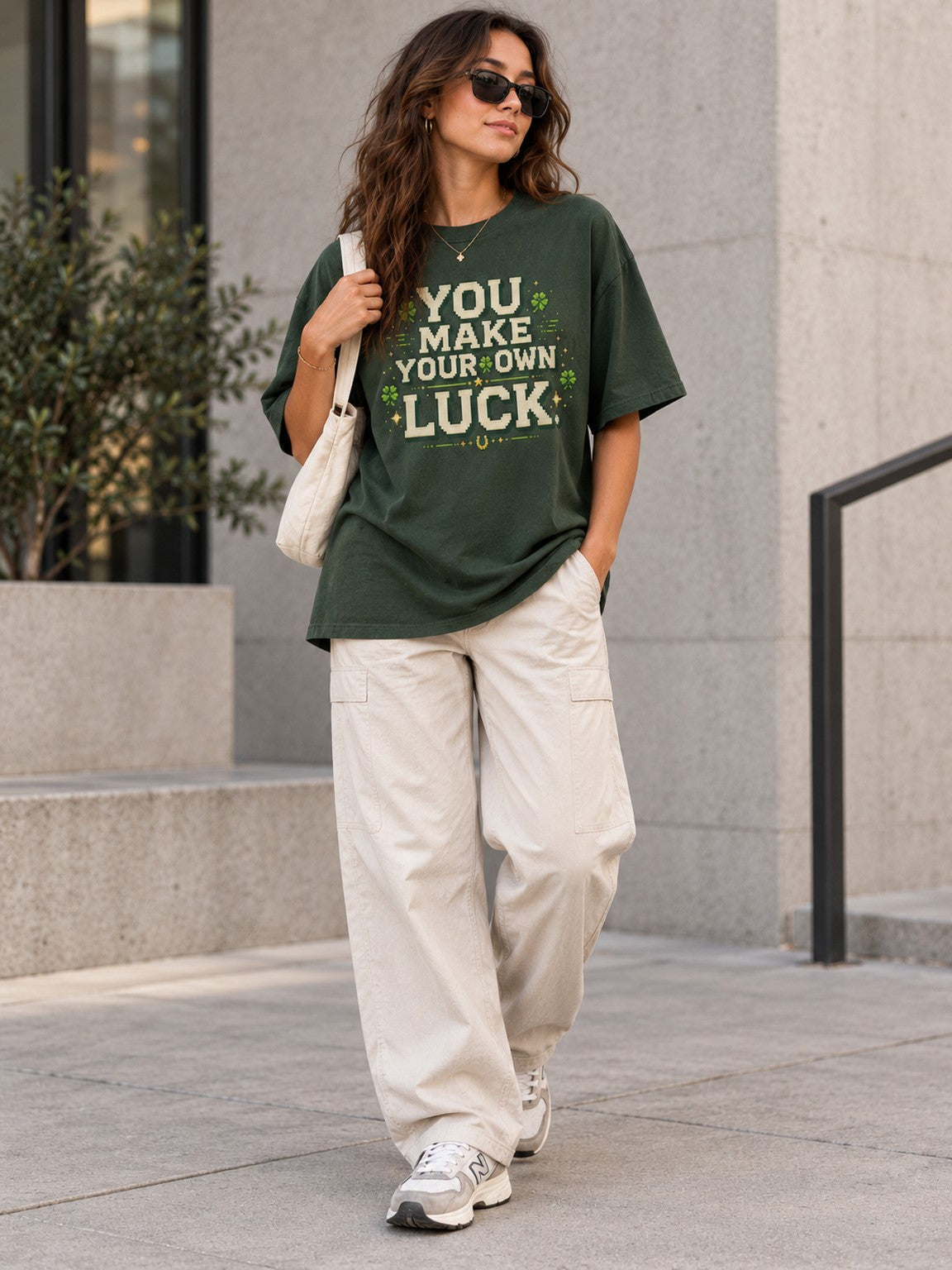 Woman wearing the Ruxel You Make Your Own Luck oversized Clover Green heavyweight tee with sunglasses and a tote bag